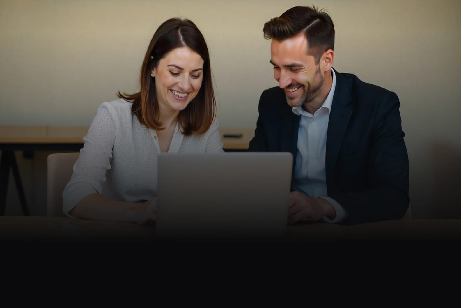Channel partner and client smiling while collaborating over a laptop.