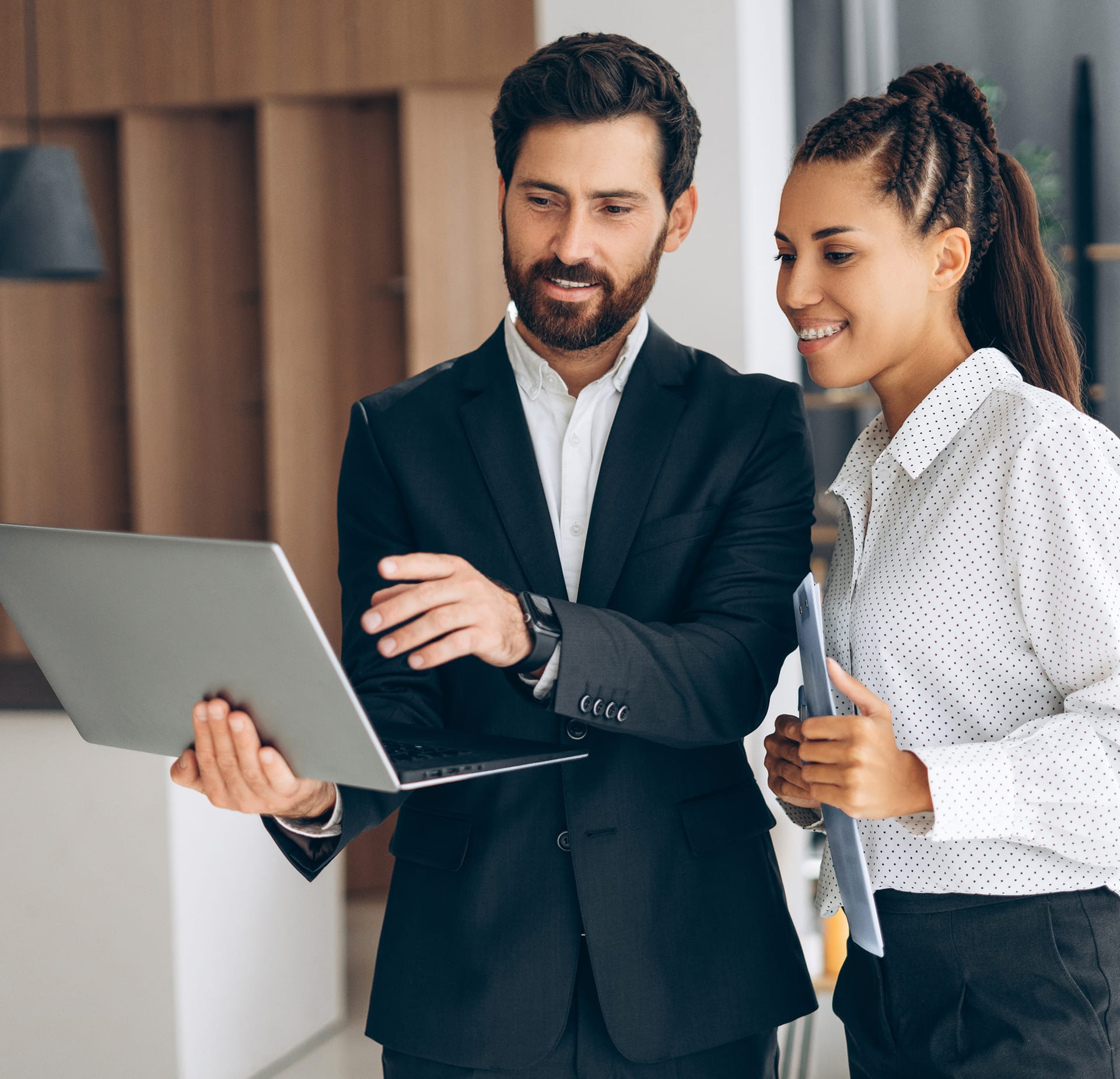 Channel partner and client smiling while collaborating over a laptop, discussing Hexnode at the office.